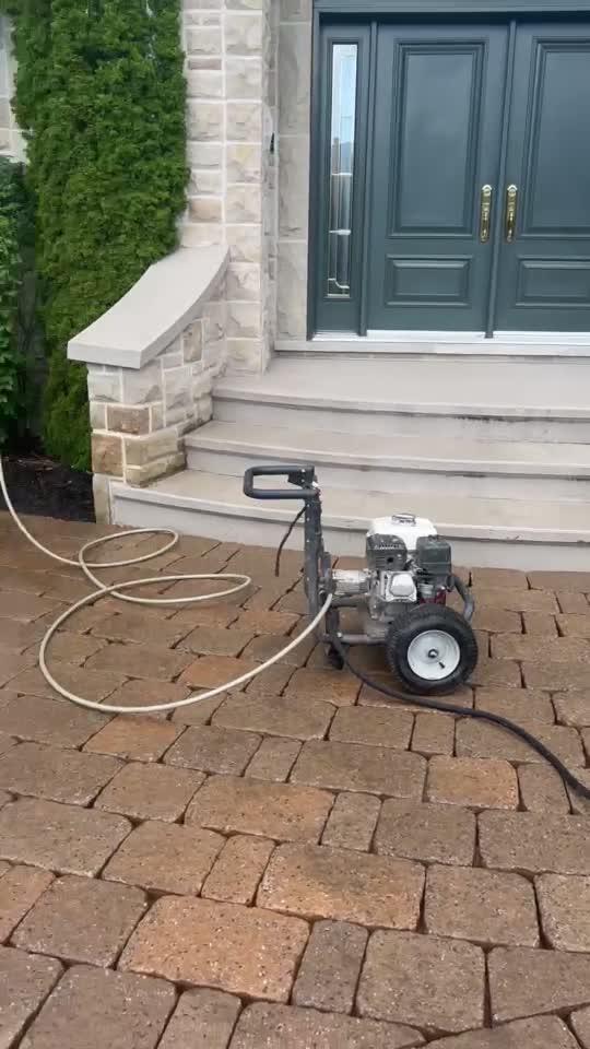 A pressure washer set up on a paver entrance